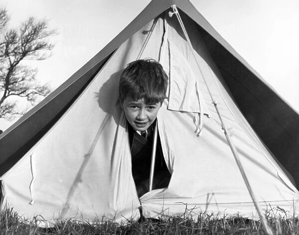 TENT BOY. A little boy peeping out of a tent! Date: 1960s