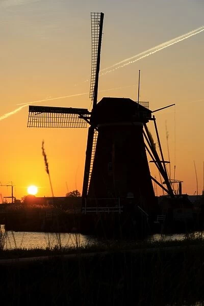 Silhouette of typical windmill framed by the fiery sky at sunset, Kinderdijk, UNESCO