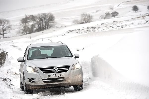 Volkswagen Tiguan 4x4 travelling along rural road after snowstorm, Cumbria, England, March