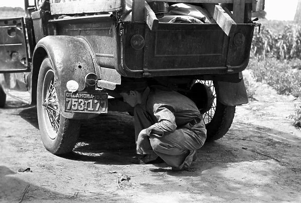 BRAKE INSPECTION, 1939. Young man examining brakes of a pick-up truck which will