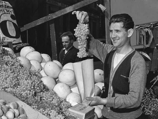 BROOKLYN: VENDOR, 1940. Pushcart vendor Al Rabinowitz bagging grapes at his produce
