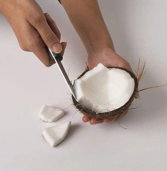 Person cutting coconut with knife, close-up