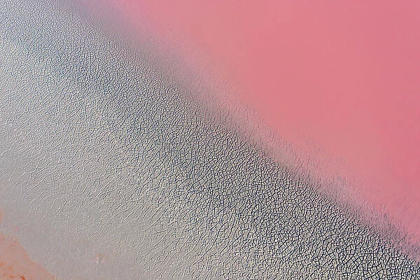 Drone view point of the pink shades of color, patterns and textures over Pink Lake waters with dark salty sandy soil