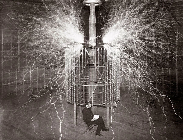 Nikola Tesla sitting in his Colorado Springs laboratory with his '