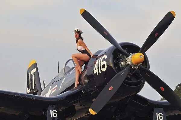 1940s style Navy pin-up girl sitting on a vintage Corsair fighter plane