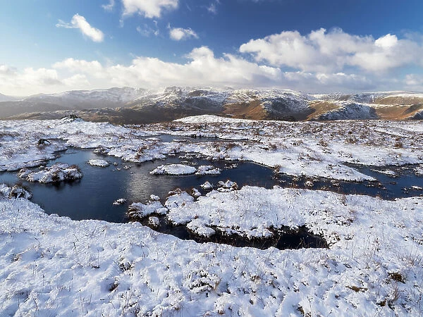 Upland peat bog on Fairfield fell covered in snow in winter, looking towards Langdale, Lake District, Cumbria, UK. January, 2022