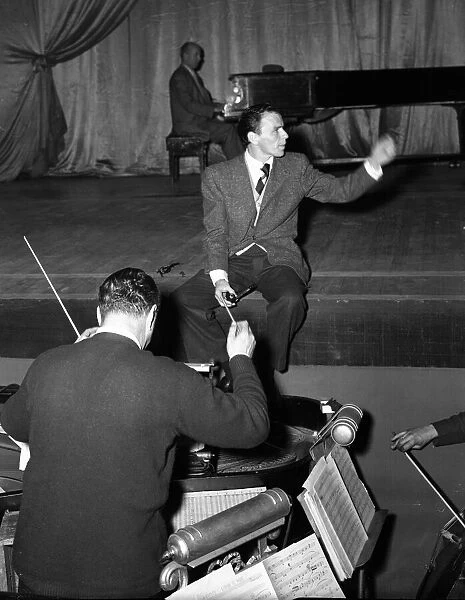 American singer and film star Frank Sinatra sitting on stage during rehearsals at