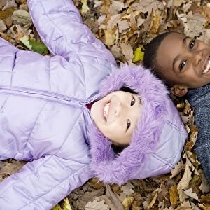 Smiling children lying on autumn leaves