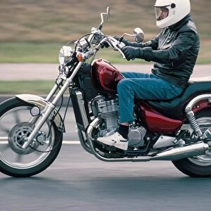 Motorcyclist rides Suzuki twin motorcycle on highway, Dawlish, Devon, England