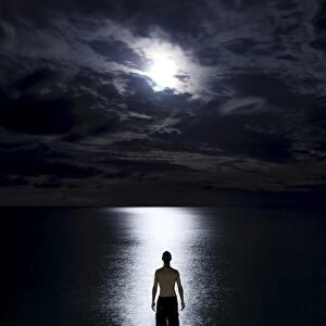 Tourist standing in the ocean watching the moon rise on Haad Rin Nai beach