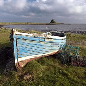 View towards Lindisfarne Castle with old fishing coble and lobster pots in the foreground