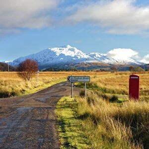 Winter view of a red telephone box and road toward snow covered Beinn Resipol mountain