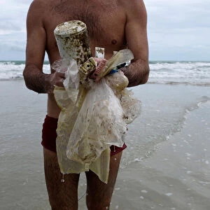 Tourist collects plastic items washed up by the sea at the Ao Phrao Beach