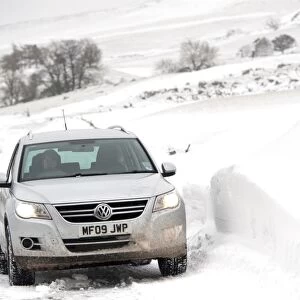 Volkswagen Tiguan 4x4 travelling along rural road after snowstorm, Cumbria, England, March