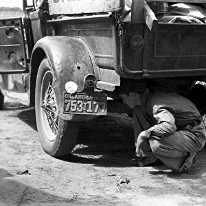 BRAKE INSPECTION, 1939. Young man examining brakes of a pick-up truck which will