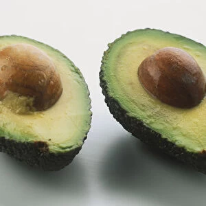 Two avocado halves, stone left in both, close up