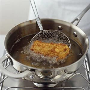Deep frying chicken in shallow pan of oil