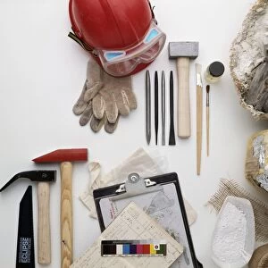 Palaeontologists equipment, including hammers, chisels, hard hat, gloves, clipboard, documents