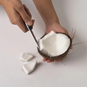 Person cutting coconut with knife, close-up