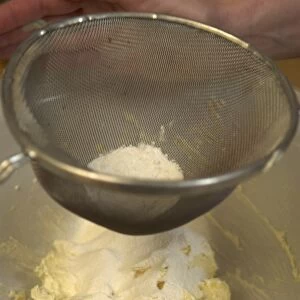 Sieved flour sifting on buttered flour in bowl