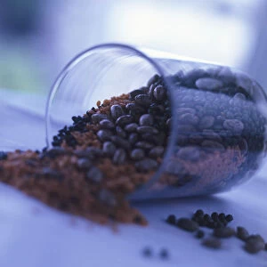 Side view of a glass with beans and lentils spilling out of it