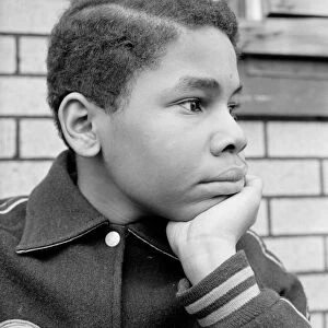 African-American teenage boy resting chin in hand, looking off to side