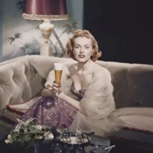 Portrait of a young woman sitting holding a beer glass