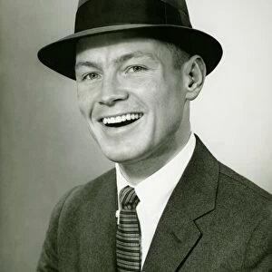Smiling man in fedora hat posing un studio, (B&W), close-up, portrait