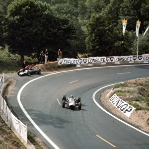1965 French Grand Prix: Graham Hill passes the retired Cooper T77 Climax of Jochen Rindt. Hill finished in 5th position