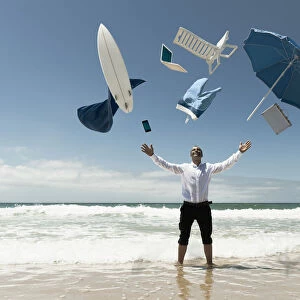 A Man Stands In The Ocean With Items From Work And Vacation Flying Over His Head; Tarifa, Cadiz, Andalusia, Spain