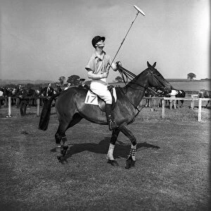 Prince Philip rides along on horseback holding a polo stick during a polo tournament